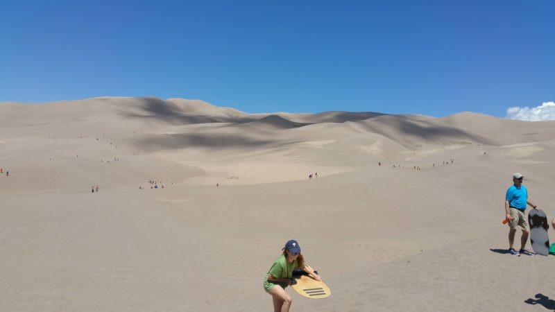 girl climbing dunes with sand board